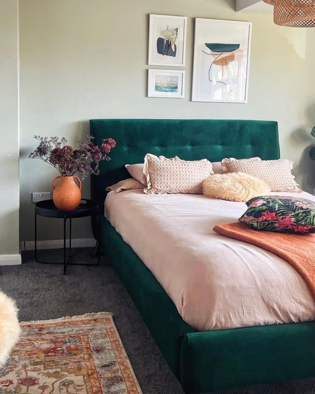 Green velvet bed with a gallery wall of framed prints above the headboard