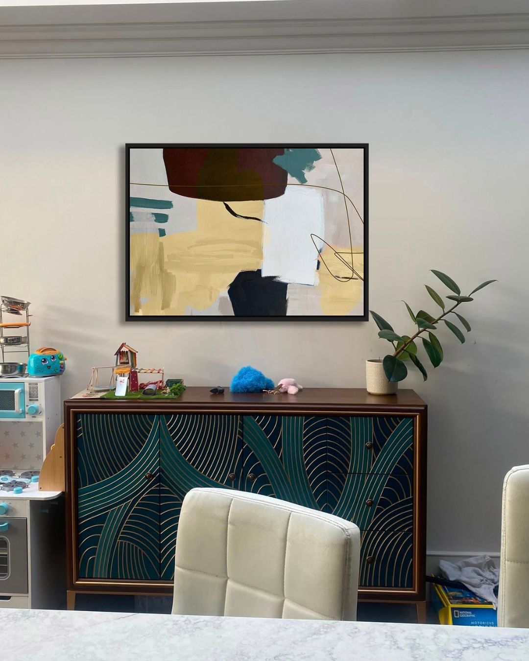 Abstract painting in mustard and navy above a dark teal sideboard